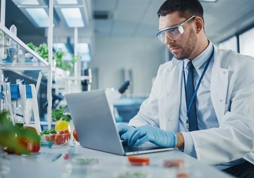 Male Scientist Working on a Laptop Computer, Creating Lab-Grown Food for Vegetarians. Microbiologist Working on Molecule Samples in Modern Laboratory with Technological Equipment.; Shutterstock ID 1919496341; other: -; purchase_order: -; client: -; job: -